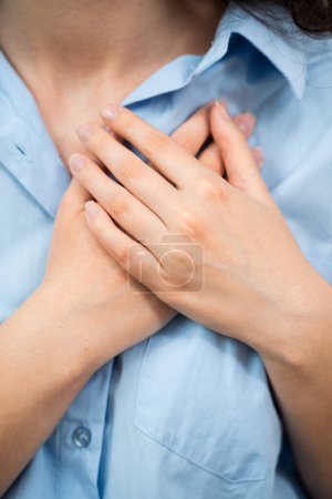 Die koronare Herzkrankheit CHD blockiert die Herzblutversorgung durch Fettsäuren in den Herzkranzgefäßen aus nächster Nähe. Attraktive Frau fasst sich die Hand ans Herz. Herzinfarkt-Schmerzen