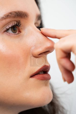 Attraktives Mädchen berührt ihre Nase vor der Septoplastik. Nasenkorrektur zur Umgestaltung der Nase und Verbesserung der Atmung