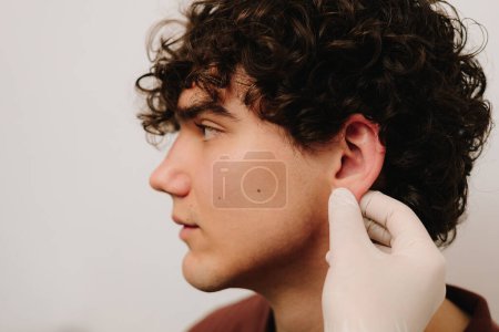 Otoplasty surgery for changing the shape, position or size of the ears. Surgeon doctor examines ear of male patient before otoplasty surgery. Preparation before otoplasty ear surgery
