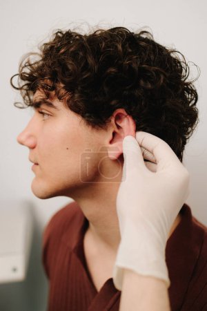 Preparation before otoplasty ear surgery. Procedure for changing the shape, position or size of the ears. Surgeon doctor examines ear of male patient before otoplasty surgery
