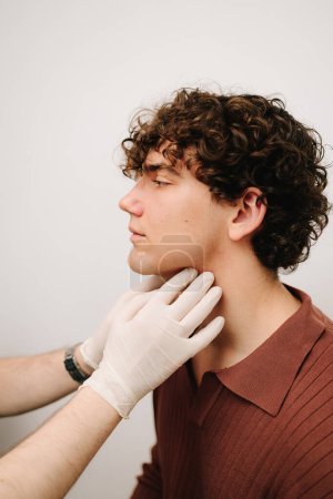 ENT doctor examined the submandibular lymph nodes of male patient. ENT doctor palpates the neck to determine inflammation of the lymph nodes of man