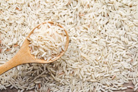 Photo for Raw rice in wooden spoon on wood background - Royalty Free Image