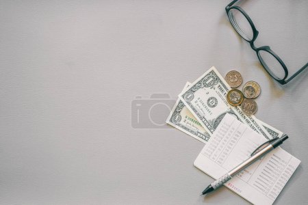 Foto de Concepto de negocio. vasos de dinero, bolígrafo y anteojos sobre mesa de madera. - Imagen libre de derechos
