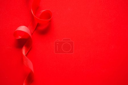 Photo for Red silk satin ribbon on a red background, top view with copyspace. - Royalty Free Image