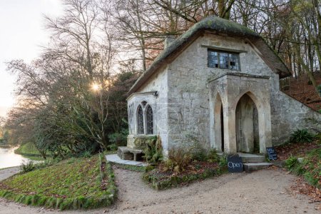 The sun setting behind the Gothic Cottage at Stourhead Gardens in Wiltshire