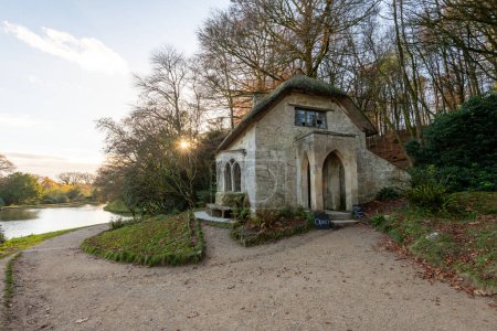 The sun setting behind the Gothic Cottage at Stourhead Gardens in Wiltshire