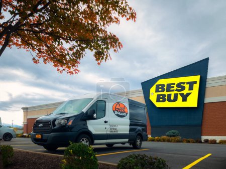 Photo for New Hartford, New York - Oct 19, 2022: Landscape Wide View of Geek Squad Black and White Van in Foreground and Best Buy Building in Background. - Royalty Free Image