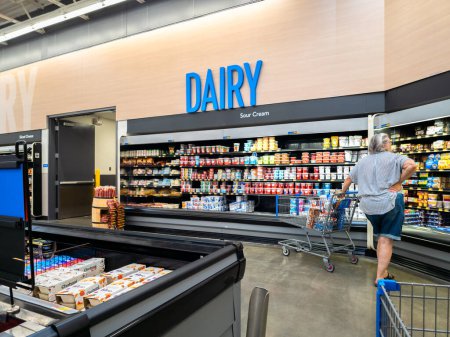 Foto de New Hartford, New York - 6 de agosto de 2023: Vista de cerca vertical de la sección de productos lácteos y crema agria de Walmart Super Center, con un cliente que comprueba los productos. - Imagen libre de derechos