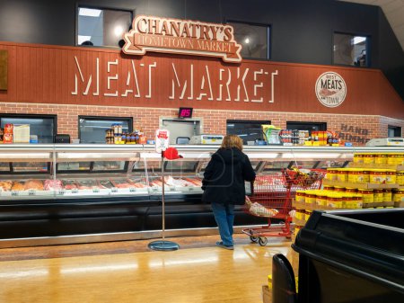 Photo for Utica, New York - Nov 6, 2023: Landscape View of the Meat Department of Chanatry's Hometown Market with a Customer Purchasing Fresh Meat.. - Royalty Free Image
