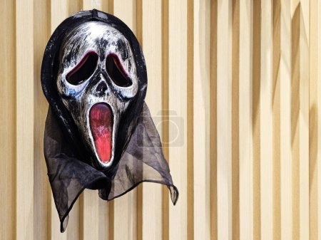 Foto de BANGKOK, TAILANDIA - 11 de octubre de 2023: Máscara de carnaval de gritos negros en la pared de madera. Scream es una franquicia americana de asesinatos y asesinatos. - Imagen libre de derechos
