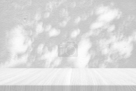 Téléchargez les photos : Table en bois blanc avec ombre d'arbre sur fond de texture murale en béton, adaptée à la présentation du produit, à l'affichage et au maquillage. - en image libre de droit