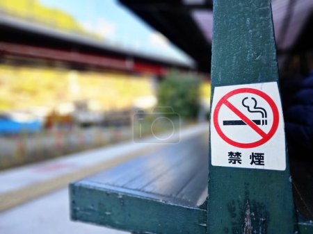Téléchargez les photos : Panneau anti-tabac sur le vieux banc en bois à la gare. (Traduire le texte est Non Fumer) - en image libre de droit