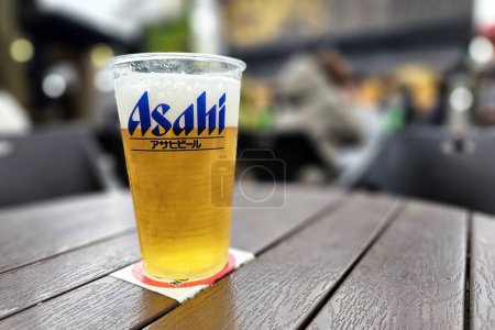 Téléchargez les photos : YUFUIN, JAPON - 12 NOVEMBRE 2023 : Asahi Beer on Wooden Table, C'est une célèbre bière japonaise super sèche et distribuée par Asahi Breweries, Ltd. - en image libre de droit