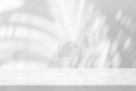 Foto de Mesa de mármol con sombra de hojas de palma sobre fondo de textura de pared de estuco, adecuada para fondo de presentación de productos, pantalla y simulacro. - Imagen libre de derechos