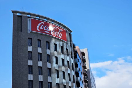Téléchargez les photos : FUKUOKA, JAPON - 14 NOVEMBRE 2023 : Panneau Coca Cola sur le bâtiment avec fond bleu ciel. La Coca-Cola Company, société américaine fondée en 1892. - en image libre de droit