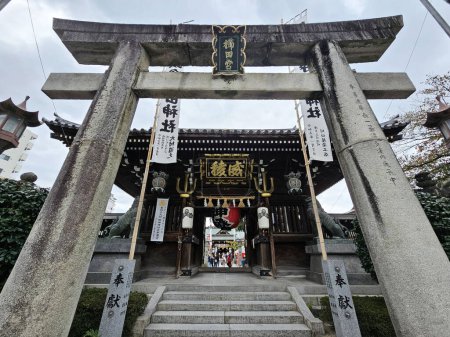 Téléchargez les photos : FUKUOKA, JAPON - 13 NOVEMBRE 2023 : Ancienne porte en pierre Torii au sanctuaire Kushida Jinja où se trouve un sanctuaire shintoïste situé à Hakata-ku, Fukuoka, Japon, a été fondée en 757. - en image libre de droit