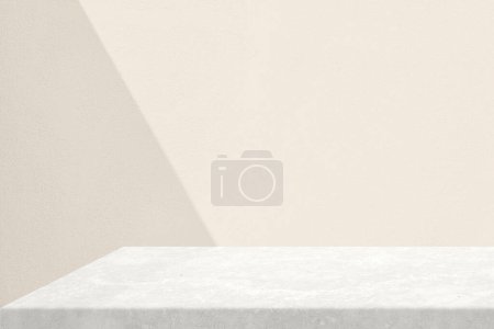 Foto de Rincón de tabla de piedra con haz de luz y sombra en fondo de pared de hormigón en el tono de color champán de vela conjunto, adecuado para el fondo de presentación de productos, pantalla y simulacro. - Imagen libre de derechos