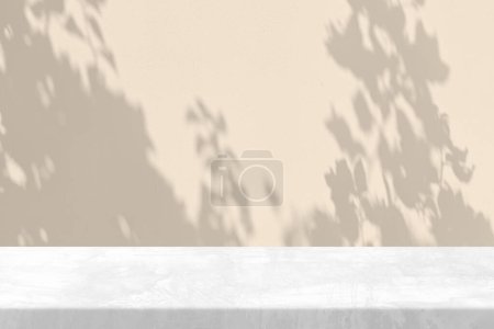 Foto de Mesa de piedra blanca con sombra de árbol en el jardín sobre fondo de textura de pared de hormigón en tono de color champán de vela establecido, adecuado para el fondo de presentación de productos, pantalla y simulacro. - Imagen libre de derechos