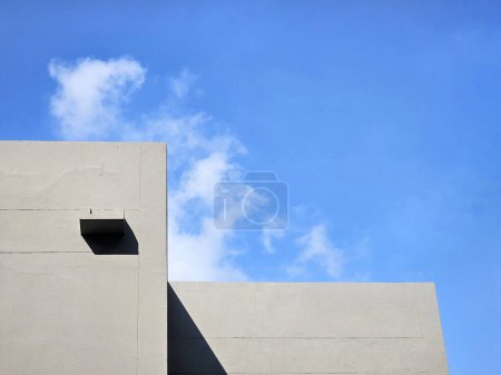 Bâtiment minimal avec nuage blanc et fond bleu ciel.
