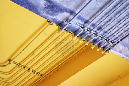 Photo for Electric metal pipe on raw and yellow concrete ceiling. - Royalty Free Image