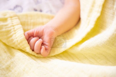 Photo for Newborn premature baby hand on pastel yellow soft muslin blanket. Copy space, space for text - Royalty Free Image