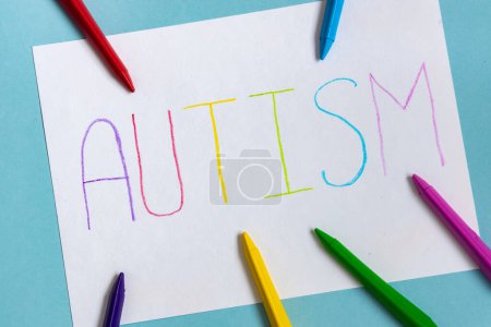 Foto de Palabra de texto autismo en hoja de papel escrita por carta colorida, sobre fondo azul - Imagen libre de derechos
