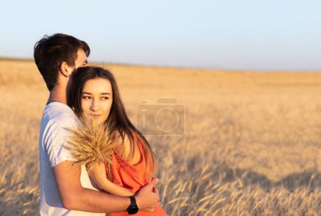 Photo for Young man hugging his girlfriend on sunset in wheat field. Copy space, love, togetherness concept - Royalty Free Image