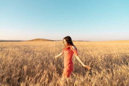Photo for Young woman in the wheat field. Connecting with nature concept. Moments of joy. Arms out to the side. Copy space - Royalty Free Image
