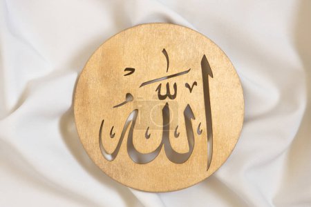 Allah bismillah names close up. Golden wooden calligraphy of islamic god. on white textile, top view