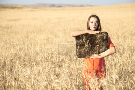 Photo for Young woman in the wheat field, holding mirror glass where reflected the dry grass. Meditation, mental health concept. Copy space - Royalty Free Image