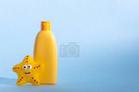 Foto de Botella de plástico amarillo con cosmético para bebés y divertido juguete de baño. El concepto de cuidado de la piel de los niños - Imagen libre de derechos
