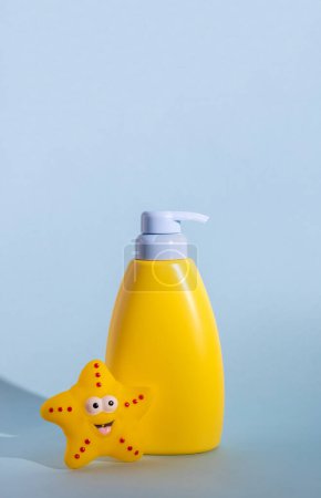 Foto de Diseño amarillo de un producto cosmético para niños con un lugar para un logotipo y un juguete de goma divertido. Protección solar para bebés, protector solar o loción corporal. Espacio para el texto. Concepto de protección verano - Imagen libre de derechos