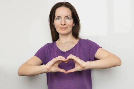 Photo for Inspire inclusion. Woman holding her hands in the shape of a heart and holding them in front of her, dressed purple t-shirt. International womens day concept - Royalty Free Image