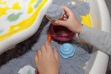Kinetischer Sand im Unterhaltungszentrum für Kinder. Kinderhände formen Formen. Selektiver Fokus