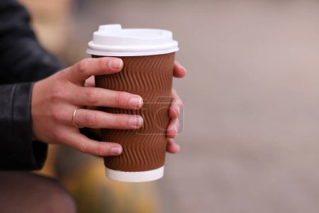 Photo for Close-up of female hands holding a large plastic disposable cup with coffee, cappuccino - Royalty Free Image
