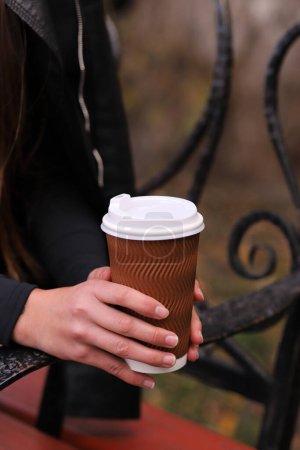 Photo for Cup with coffee in female hands, street photo, fast food concept. Vertical Orientation - Royalty Free Image