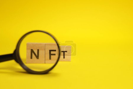 Foto de Word NFT, non-fungible token through a magnifying glass. NFT analysis concept - Imagen libre de derechos