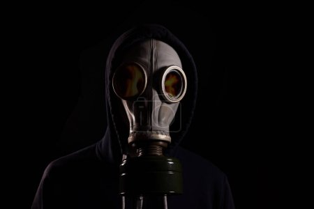 Photo for A man in a hood in a gas mask with a reflection of fire in the glasses. The concept of a fire. - Royalty Free Image
