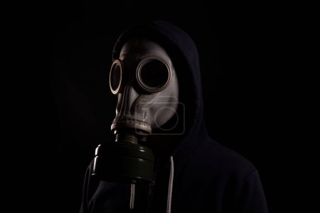 Photo for Man in a hood in a gas mask on a black background, the concept of environmental pollution, post-apocalypse - Royalty Free Image