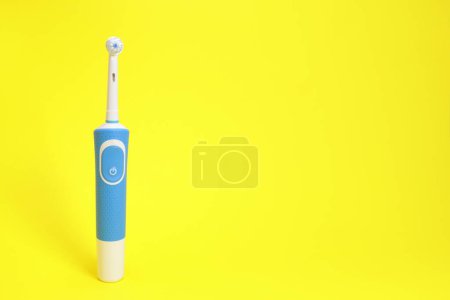 Téléchargez les photos : Brosse à dents électrique sur fond jaune. espace de copie pour le texte - en image libre de droit