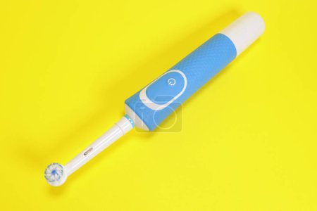 Téléchargez les photos : Brosse à dents électrique sur fond jaune - en image libre de droit