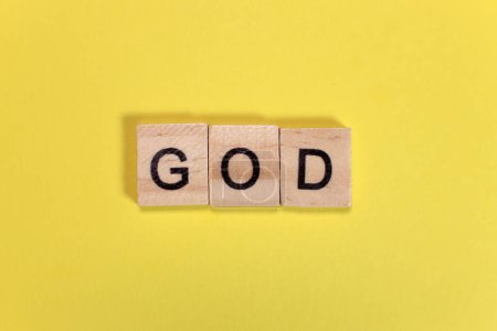 Téléchargez les photos : Mot de Dieu de lettres en bois sur fond jaune - en image libre de droit