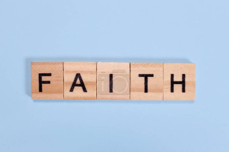 Téléchargez les photos : Mot de foi fabriqué à partir de blocs de bois sur fond bleu - en image libre de droit