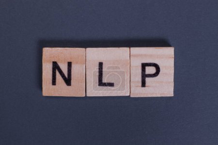 NLP steht für Natural Language Processing aus Holzbuchstaben auf grauem Hintergrund