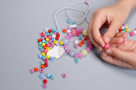 Girl making a bracelet from colored beads close-up