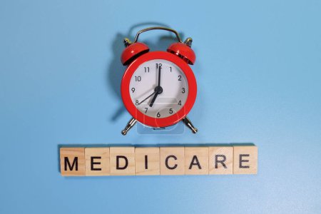 Foto de Palabra de Medicare y reloj despertador sobre fondo azul - Imagen libre de derechos