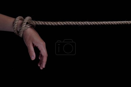 Foto de Manos atadas con una cuerda sobre un fondo negro. espacio de copia para texto - Imagen libre de derechos