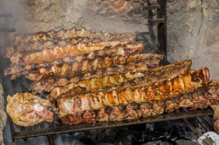 Foto de Cocinar algunos filetes, costillas y embutidos en una gran barbacoa con fuego de madera - Imagen libre de derechos