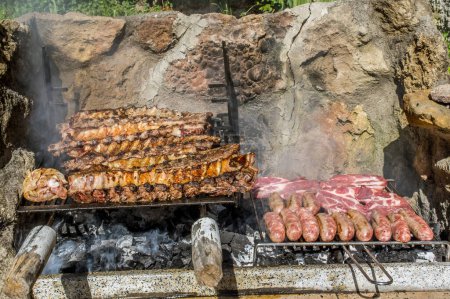 Foto de Cocinar algunos filetes, costillas y embutidos en una gran barbacoa con fuego de madera - Imagen libre de derechos