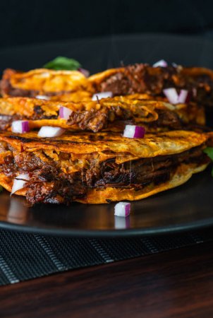 Téléchargez les photos : 3 tacos de birria de bœuf croustillants et juteux empilés sur une assiette noire. Mise en page appétissante de la nourriture mexicaine incroyable à Tijuana, Mexique. - en image libre de droit